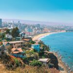 Vista panorámica de Valparaíso e Viña del Mar con colores vibrantes al atardecer, destacando la arquitectura y la costa